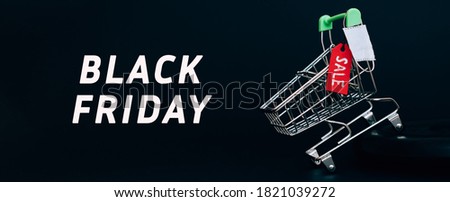 Shoping cart with red label with the inscription SALE on black background.Miniature protective medical mask on the cart.The inscription BLACK FRIDAY.Black Friday and coronavirus concept,copy space