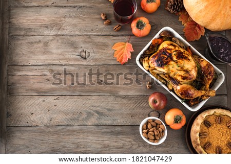 Thanksgiving dinner with chicken, cranberry sauce, pumpkin pie, wine, seasonal vegetables and fruits on wooden table, copy space. Traditional autumn holiday food concept. 