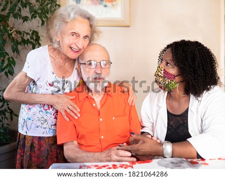 Horizontal portrait of an African American medical assistant helping an ederly couple at home in times of Covid19 pandemic