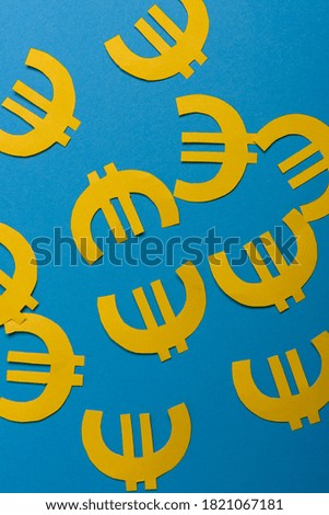 Paper yellow symbols of euro currency on blue background. View from above with copy space