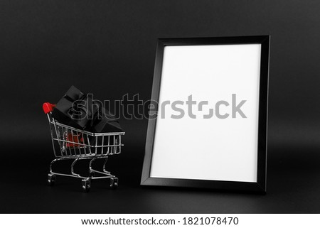 A frame and shopping cart with gifts on a black background, a blank for the design, concept. Copy space.