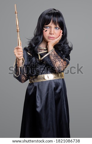 little girl in witch costume on grey background