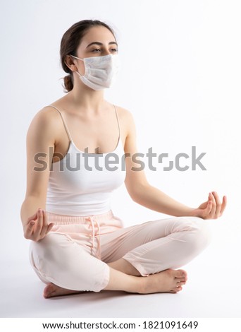 Young woman wearing a face mask,  practicing yoga on white background