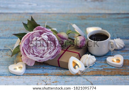 pink peony with buds, coffee cup, heart shaped light bulbs on blue wooden background