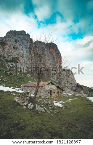 A house or refuge in the middle of the mountains of asturias and lake of covadonga during winter with a green grass and snow