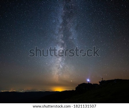 Young couple enjoying the beautiful view of the Milky Way on top of Parang mountains in Romania.