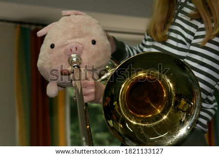 Funny Spider pig playing the trombone . Stuff animal placed in front of metal wind instrument . Fluffy and fat spider piggy during jazz solo performance . female trombone player in action. loud t-bone