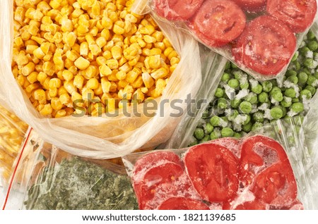 Set of frozen food packed in bags. Store vegetables for the winter, top view. Tomato, green peas, corn, greens.