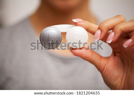 Woman holding plastic container with contact lenses
