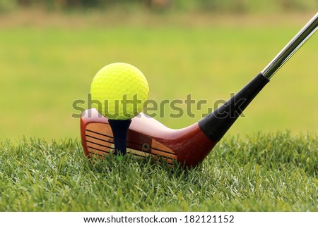 Golf ball and Wooden Driver on green grass background