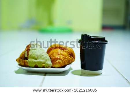croissant coated green tea cream with black paper coffee mugs