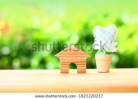 wooden small home with little heart in pot on blur green background
