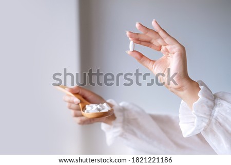 Woman in white blouse holding in hand wooden spoon with magnesium or calcium supplement capsule. Bioactive additive woman pharmacy. Vitamin mineral treatment. Autumn health care concept Royalty-Free Stock Photo #1821221186