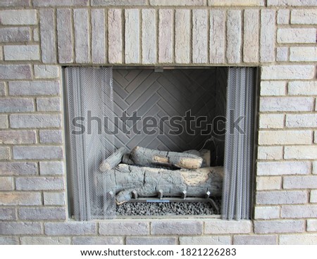 Closeup of an old stone fireplace on an outdoor patio with logs inside 