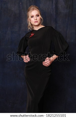  cropped image of an elegant blonde lady poses for the advertisement of a women's clothing store dressed in a black dress with brooches and holding hands on waist. minimalistic style 
