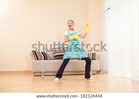 funny woman mopping floor and playing. beautiful girl playing music using mop Royalty-Free Stock Photo #182126444