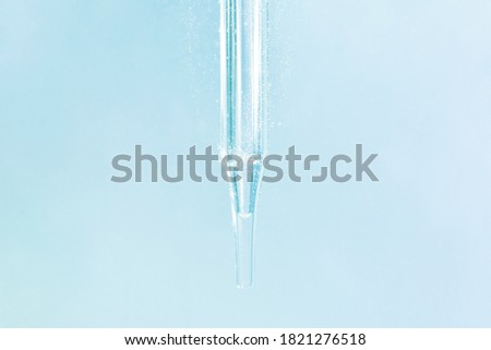 serum or liquid particle from laboratory glass pipette with blue water background