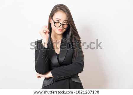 Chinese business woman in black office clothes with straight face expressions on white background.