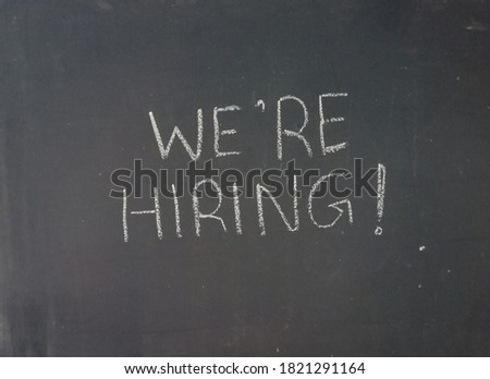"We hiring" is written on a blackboard.