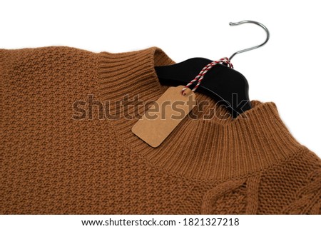 Knitted sweater hangs on a black hanger with a tag. Isolated on white.