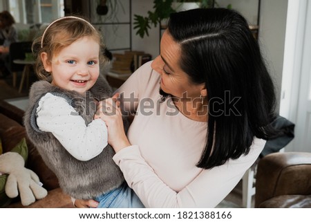 Young baby girl and her mother embrace and hug, stickling and laughter
