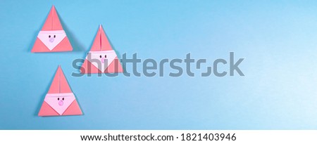 3 Origami Xmas pink Santa claus on a blue background and copy space available