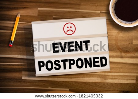Lightbox or light box with the words for This event is postponed on wooden table background Royalty-Free Stock Photo #1821405332