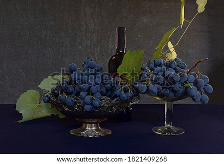 Two grape varieties in vases and a bottle of wine.