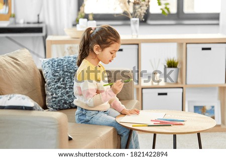 childhood, creativity and art concept - little girl drawing with coloring pencils at home