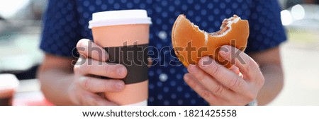 Man holds glass with hot coffee and hamburger in his hand. Fast food concept