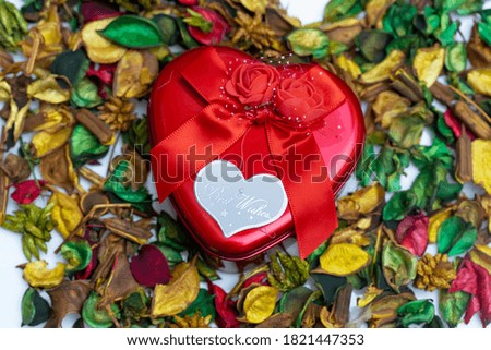 extreme close up of red hot heart box with red bow on top placed within the dried flowers