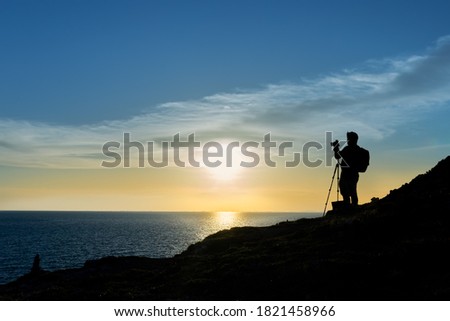 Silhouette of a nature photographer framing a shot, taking pictures at sunset on the beach