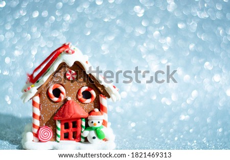 Gingerbread house on the background of new year's blurred bokeh. With Christmas tree branches and cranberry berries. Christmas food decoration, decorated in the form of country hut sweets.