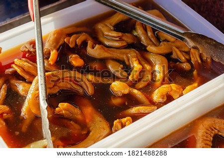 Unusual, strange, and disgusting food. Duck feet in sauce or marinade.  Street food in China. Blurred image with shallow depth of field.
