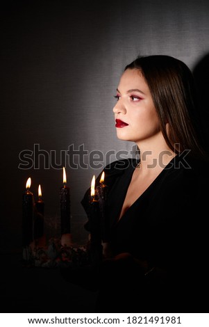 Woman holding burning candles in dark room, Halloween party