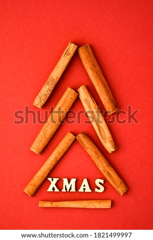 Text XMAS made of wooden letters with cinnamon christmas tree on red background. Banner size. New year and Merry Christmas greeting card. Wood letter