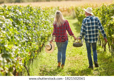 Happy young couple on a trip in the vineyard with basket for a picnic