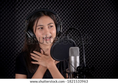 Young lady singing with smile in music studio