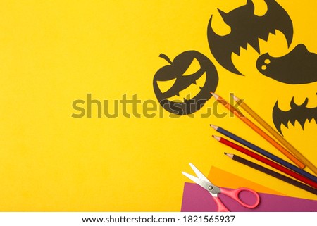 Halloween background. Black bats cut from paper on a yellow background. Making Halloween home decor from colored paper.