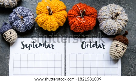 Flat lay calendar with crochet pumpkin on a dark background. September and October 2020. top view.