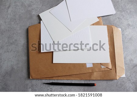 White sheets of paper, craft envelopes on a concrete background. Place for text, illustrations.