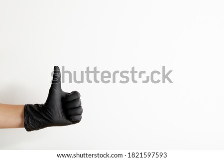 Female hand in black latex gloves shows thumb up gesture, isolated on white background with free space for text
