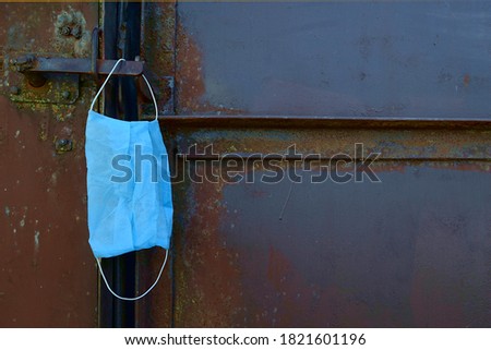 medical mask hanging on an old metal gate