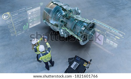 Industry 4.0 Factory: Two Engineers Uses Digital Tablet Computer with Augmented Reality Software Visualize 3D Model of a Jet Turbine Engine. Aircraft Maintenance and Diagnostics. High Angle Shot Royalty-Free Stock Photo #1821601766