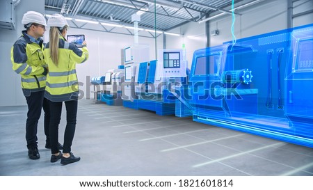 Two Engineers Use Digital Tablet Computer with Augmented Reality Software to Create 3D CNC Machinery, Equipment Visualization in Factory. Industry 4.0 Facility. Augmented Reality Graphics VFX Effects Royalty-Free Stock Photo #1821601814