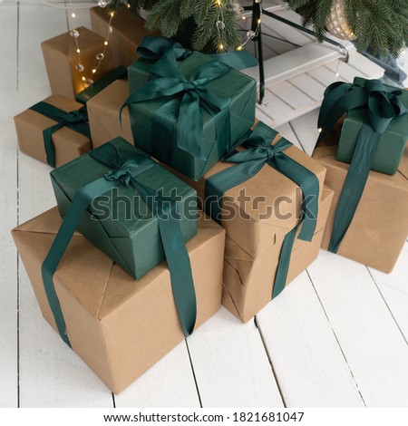 New Years presents lie under the Tree. Gifts in brown boxes and green packaging. Boxes decorated with ribbons and bows. Close up shot. High quality photo.