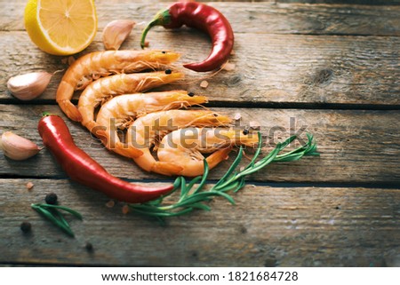 fresh raw shrimps on a craft wooden background with lemon and spices. Copy space.