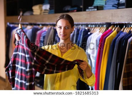 Cute woman buys checkered shirt in the fashion store. High quality photo