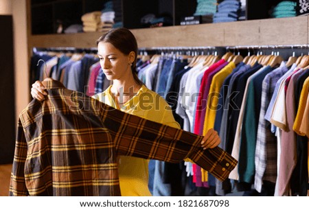 Cute woman buys checkered shirt in the fashion store. High quality photo