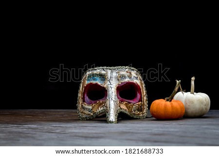 Halloween Pumpkin on wood board with homemade plague mask dark background copy space